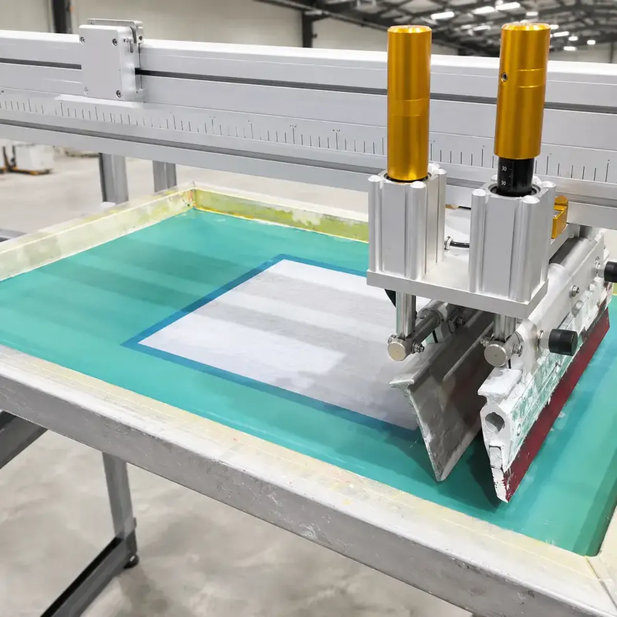 Automated squeegee applying screen pre-treatment liquid uniformly on hybrid DTG printer carousel